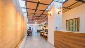 A modern office space with a long corridor, wooden reception desk, and a wall with a vertical garden. - Fortune Hotel (Taining)