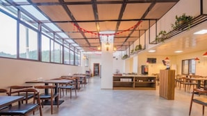 A spacious dining area with long tables and chairs, a central counter, and large windows offering views. - Fortune Hotel (Taining)