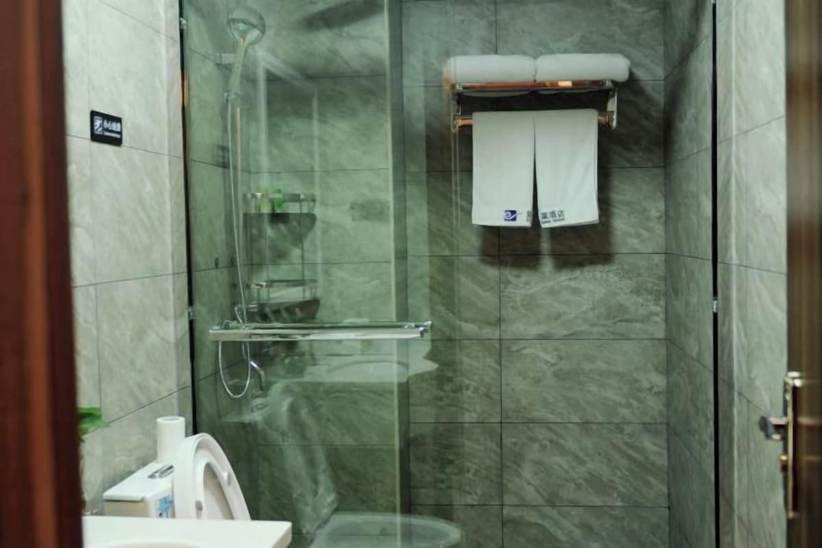 A glass-enclosed shower stall with a towel rack, a toilet, and a sink.