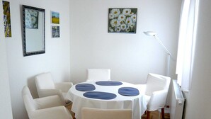 Zona pranzo con tavolo rotondo, quattro sedie e tovaglia bianca.