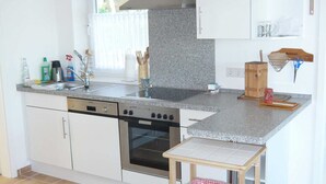 Cucina con mobili bianchi, cappa in acciaio inossidabile, forno integrato e piano di lavoro in granito.