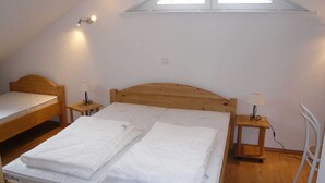 Een slaapzaal met twee eenpersoonsbedden, een dakraam en een witte stoel.