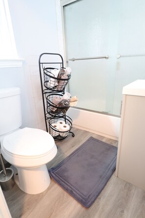 A compact bathroom with a toilet, towel rack, and non-slip mat, featuring a frosted glass door.