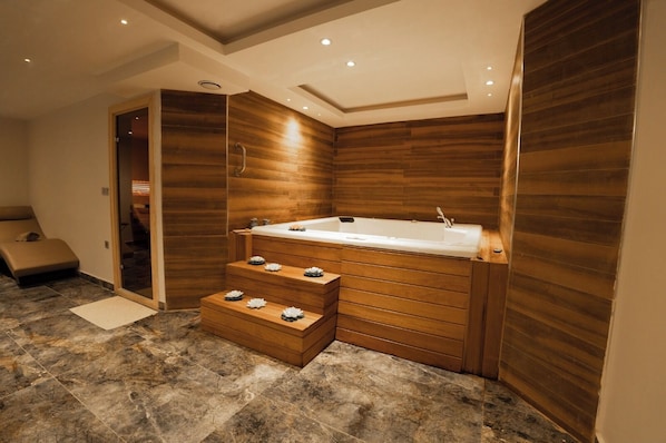 Un baño moderno con una bañera independiente, paneles de madera y piso de mármol.