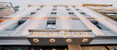 Un hôtel avec une enseigne indiquant « BUSINESS Life Hotel » et une façade moderne dotée de nombreuses fenêtres.