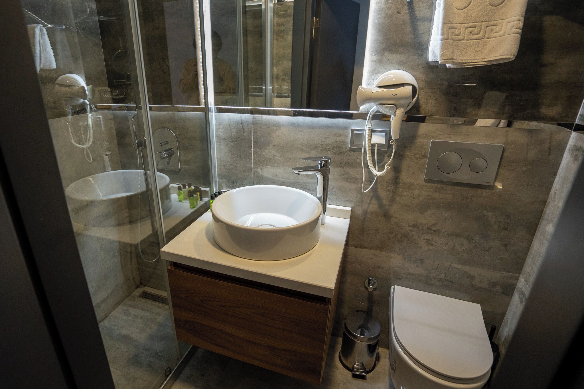 Une salle de bain moderne avec une douche à parois de verre, un lavabo blanc et des toilettes.