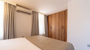 A hotel room with a bed, curtains, an air conditioning unit, and wooden wardrobe doors. - Business Life Hotel & SPA Bakırköy (Istanbul)