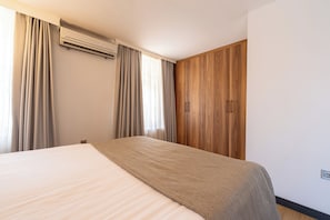 A hotel room with a bed, curtains, an air conditioning unit, and wooden wardrobe doors. - Business Life Hotel & SPA Bakırköy (Istanbul)