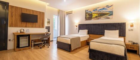 A hotel room with two beds, a desk, a TV, and a painting on the wall.