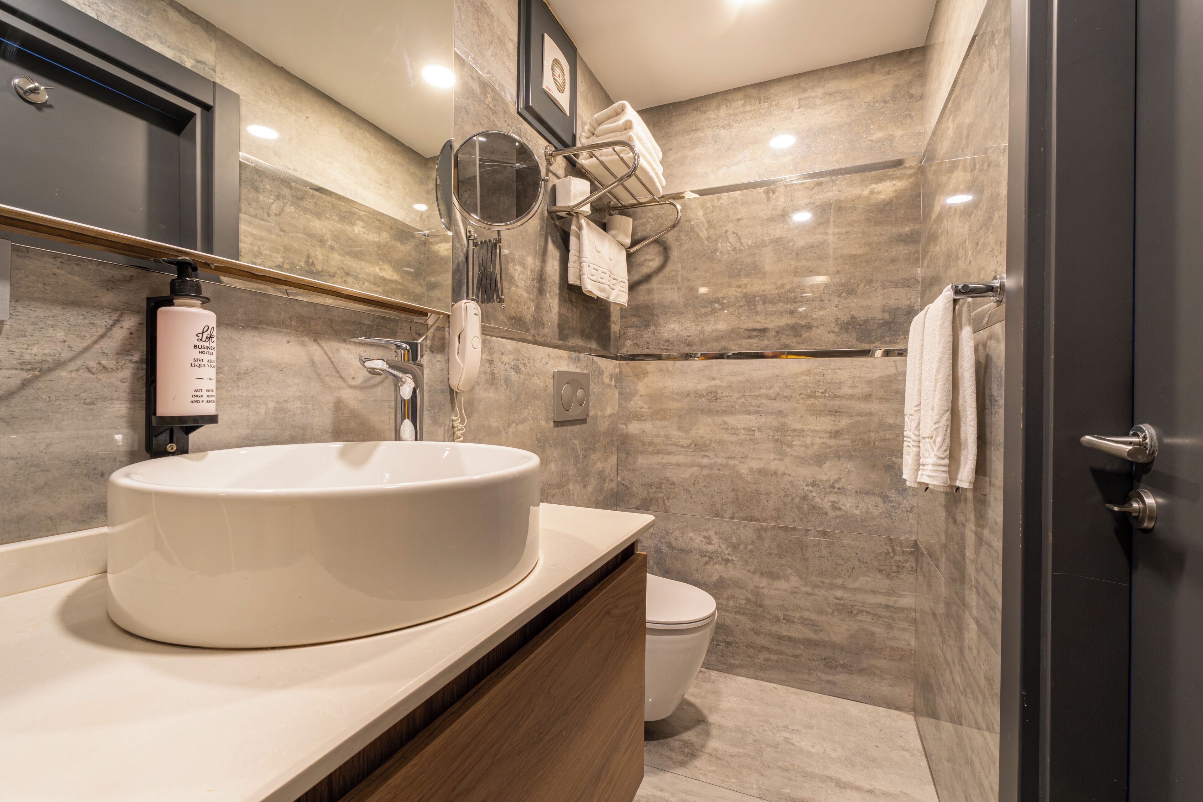 A modern bathroom with a round sink, a toilet, and a shower area.