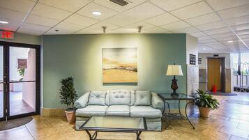 A lobby with a sofa, a coffee table, a lamp, and a painting on the wall.