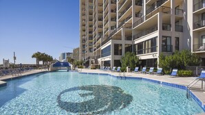 A clear swimming pool with lounge chairs and a modern building in the background. - Phoenix East 508 | Breathtaking Gulf Views | Family Favorite Condo | My Beach Getaways (Orange Beach)