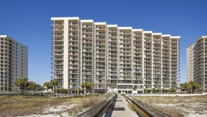 A high-rise hotel with multiple balconies, a beachside location, and a wooden boardwalk leading to the entrance. - Phoenix East 508 | Breathtaking Gulf Views | Family Favorite Condo | My Beach Getaways (Orange Beach)