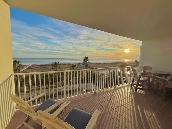 Een balkon met uitzicht op het strand en de zonsondergang.