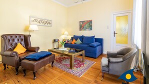 A living room with a brown leather armchair, a blue sofa, a grey armchair, a coffee table, and a chandelier. - Beach villa Whg 02 - SVB 02 (Heringsdorf)