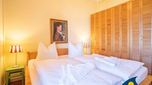 A hotel room with a large bed, two bedside lamps, a wooden wardrobe, and a framed picture on the wall. - Beach villa Whg 02 - SVB 02 (Heringsdorf)