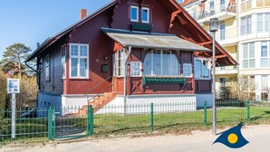 A red wooden building with white trim, a green awning, and a small porch. - Beach villa Whg 02 - SVB 02 (Heringsdorf)