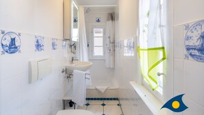 A bathroom with a sink, mirror, and window with a curtain. - Beach villa Whg 01 - SVB 01 (Heringsdorf)