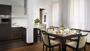 A modern hotel room with a kitchen area, dining table, and breakfast setup. - Milano Castello Luxury Apartment (Milan)