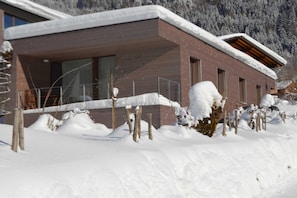 Un bâtiment moderne avec une façade en briques, de grandes fenêtres et un toit recouvert de neige.