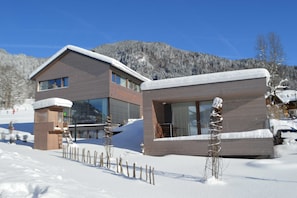 A modern two-story building with large windows and a ski lift in the background.