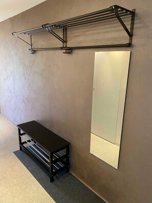 A room with a metal shelf unit, a bench, and a large mirror on the wall. - House Christiane, Austria (Schoppernau)