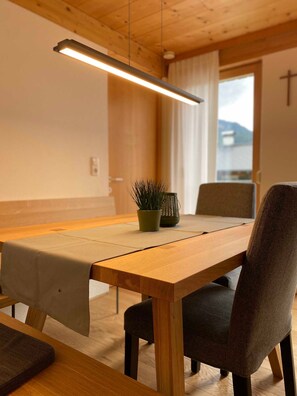 A wooden dining table with a light fixture above, a potted plant, and a chair.