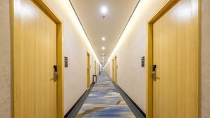 A hotel hallway with wooden doors on both sides, a carpeted floor, and a ceiling with recessed lighting. - Rest Hotel (Lanzhou West Railway Station Lanzhou Old Street) (Lanzhou)