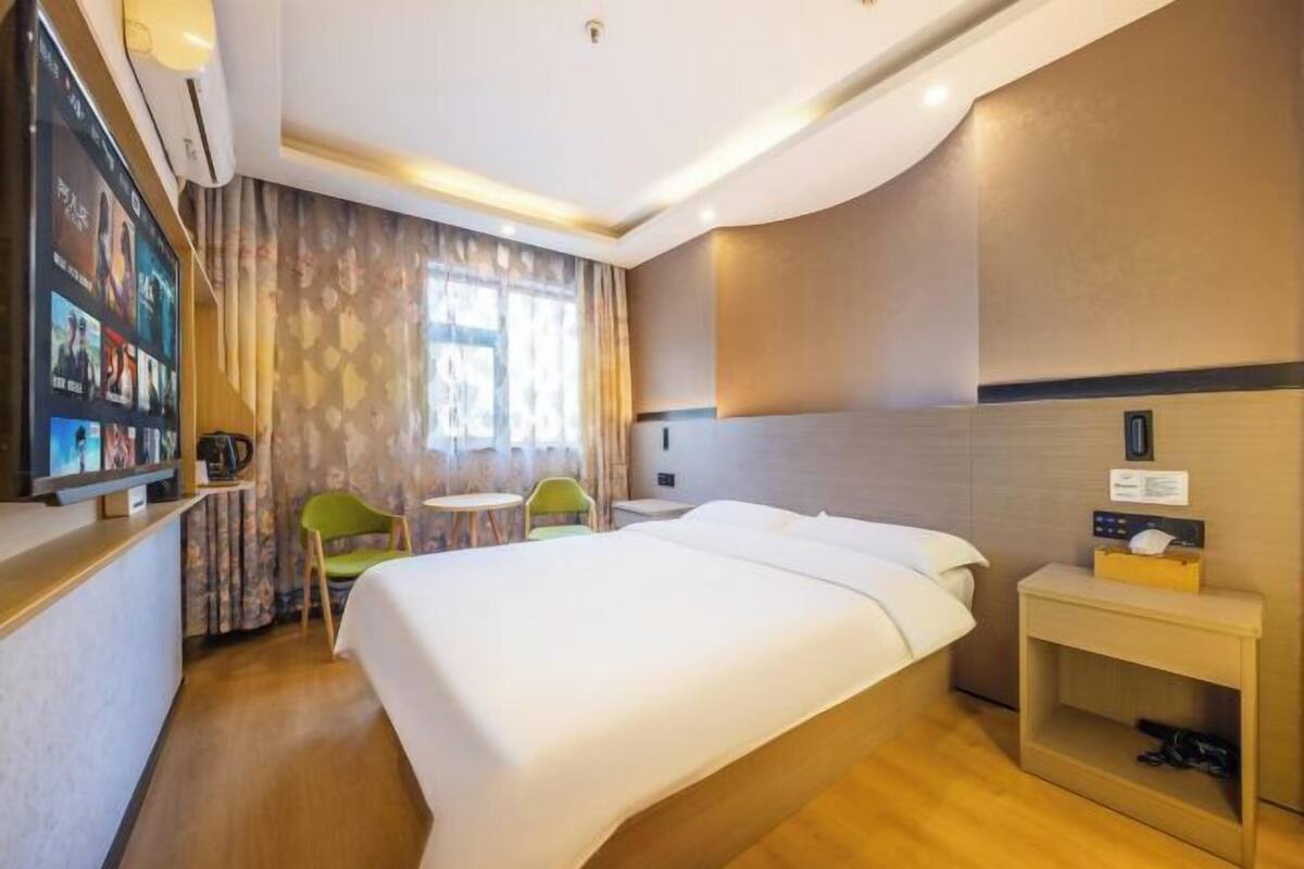 Habitación de hotel con cama, escritorio, silla, mesita y televisor.