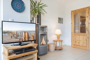Un salon avec une télévision, une cheminée, une porte en bois et une plante.