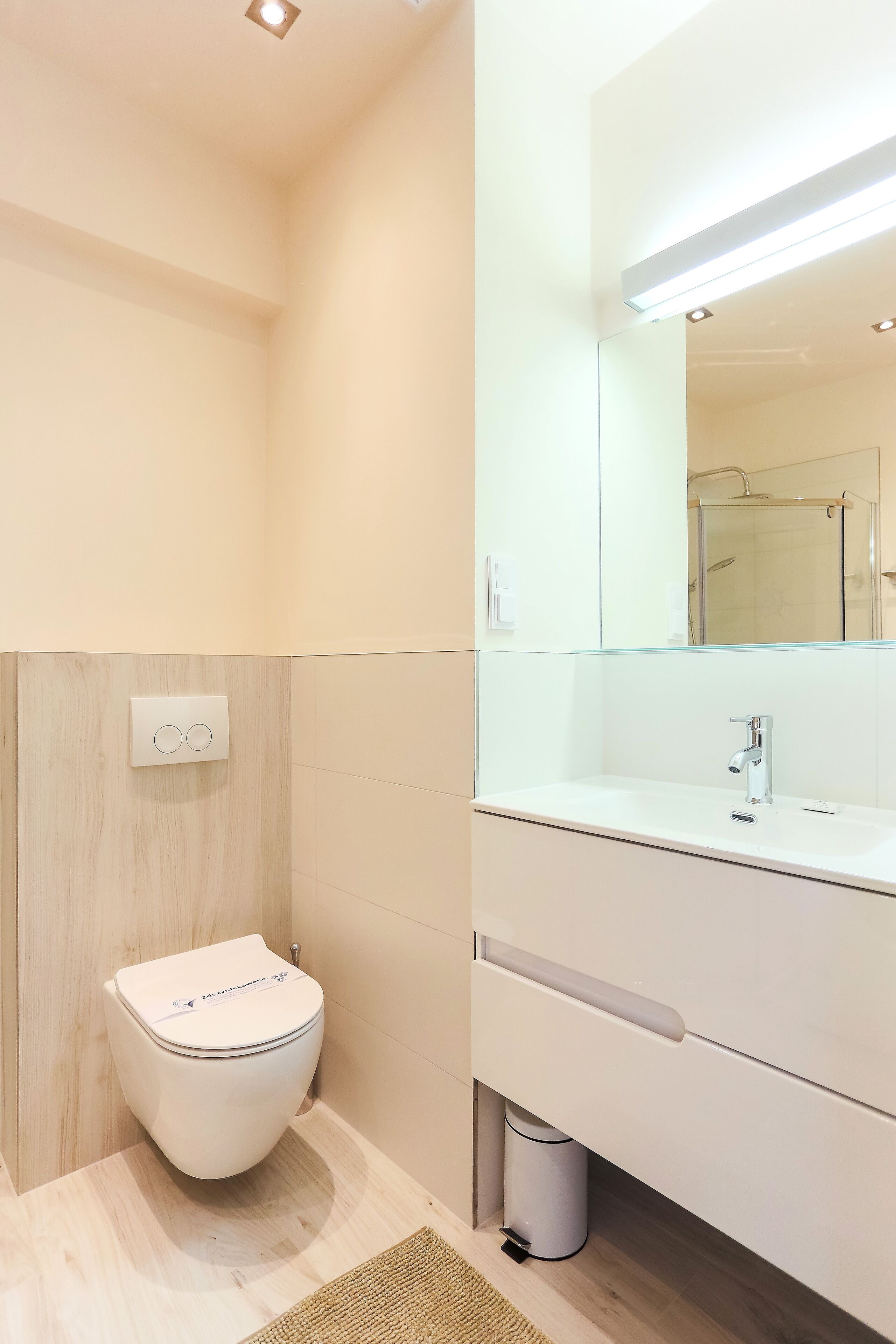 Ein modernes Badezimmer mit Toilette, Waschbecken und Spiegel.