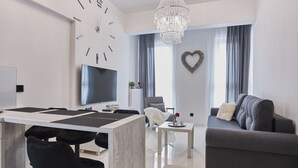 Un salon moderne comprenant un coin repas, un lustre, une grande horloge murale et une décoration en forme de cœur.