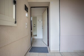 Un pasillo con una puerta que da a una habitación, un letrero en la pared y un felpudo.