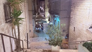 A narrow alleyway with a staircase leading to a courtyard. There are potted plants and outdoor seating areas. - ROMANTIC OR FAMILY RENTAL (Ceglie Messapica)