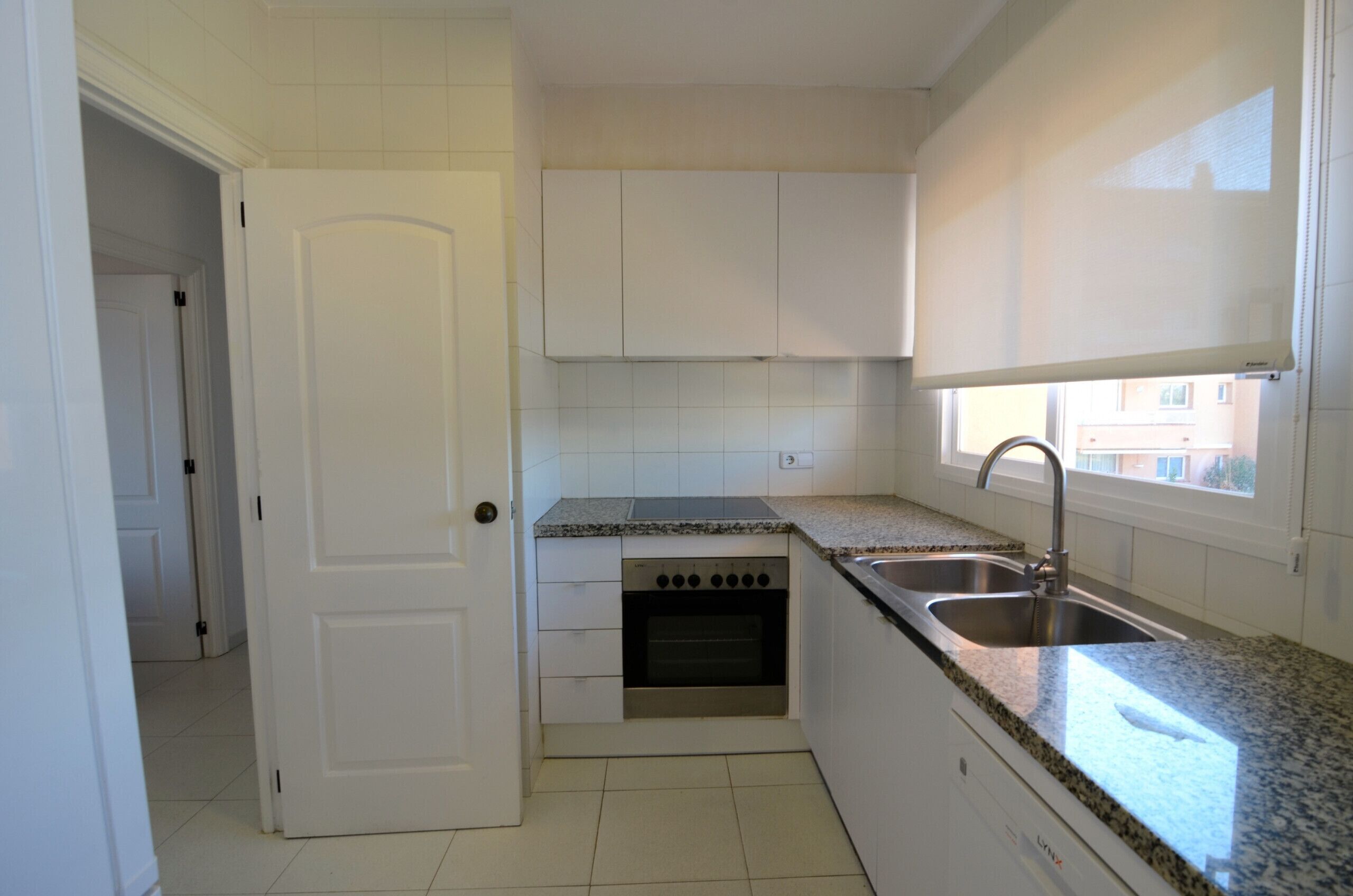 A kitchen with white cabinets, a stainless steel sink, and a built-in oven.