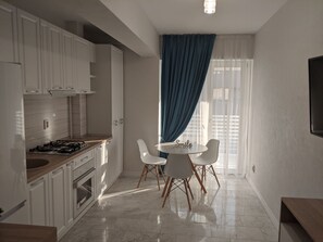 Una cucina moderna con mobili bianchi, piano cottura a gas e zona pranzo con tavolo e sedie.