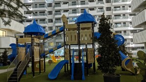 A playground with slides and climbing structures, surrounded by a building with multiple balconies. - Premium Apartment in Copou (Iași)