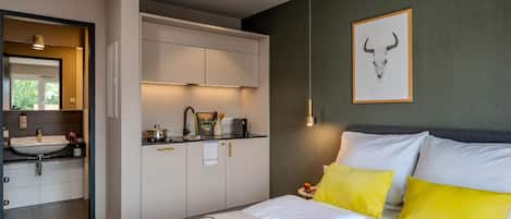 A modern bedroom with a bed, bedside table, and a framed picture on the wall.