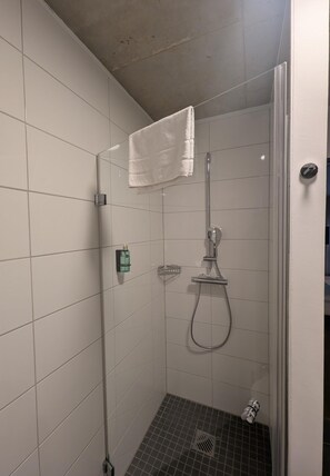 A shower with a glass door, a towel hanging on the wall, and a small bottle on the wall. - ipartment Wolfsburg @HOME by Best Western (Wolfsburg)