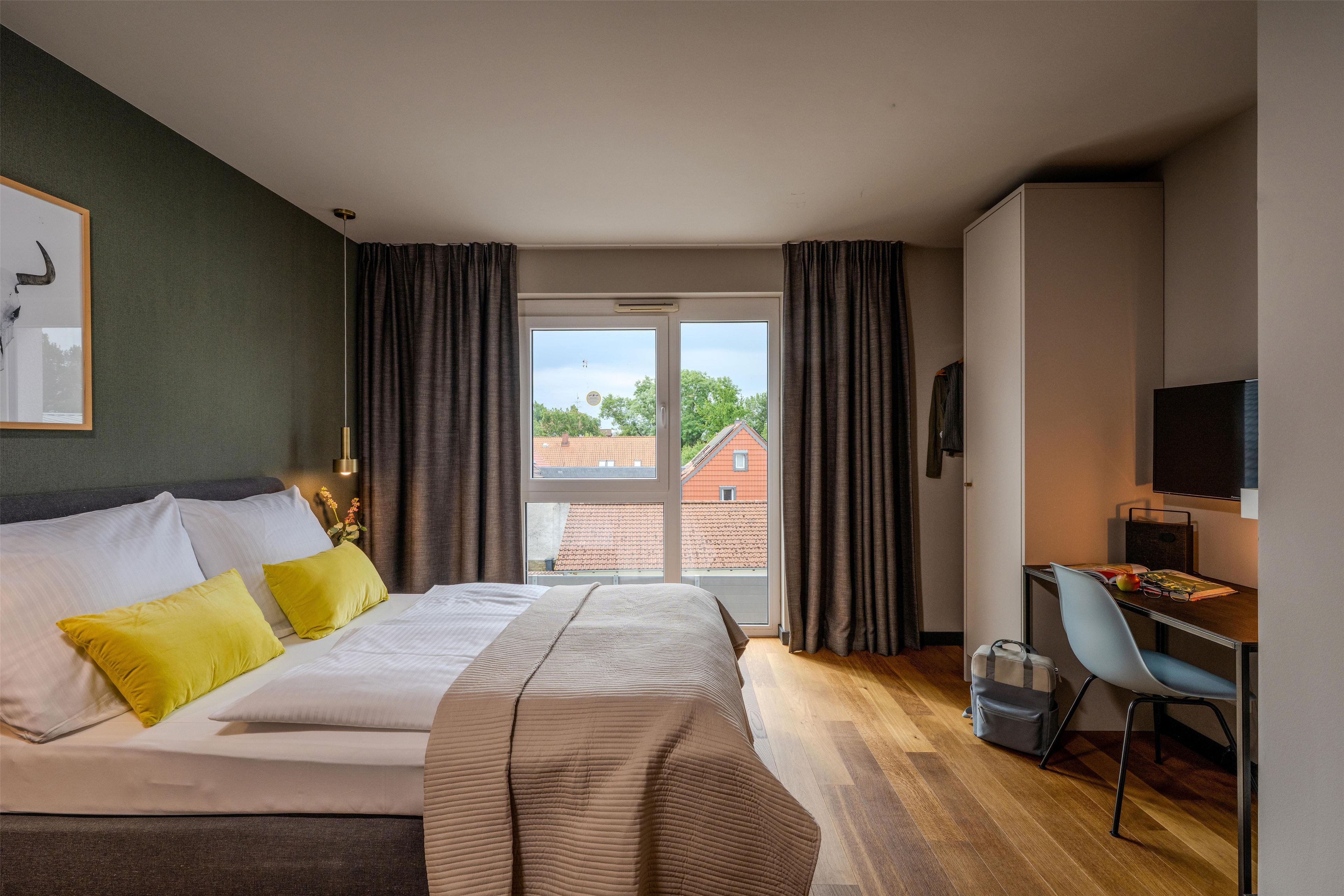 A hotel room with a bed, a desk, a chair, and a TV.