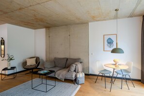 Una sala de estar moderna con un sofá, una mesa de centro, una mesita auxiliar y un comedor con sillas y una mesa.