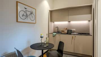 Eine kompakte Küche mit Essbereich, einem Heizkörper und einer gerahmten Illustration von einem Fahrrad an der Wand.