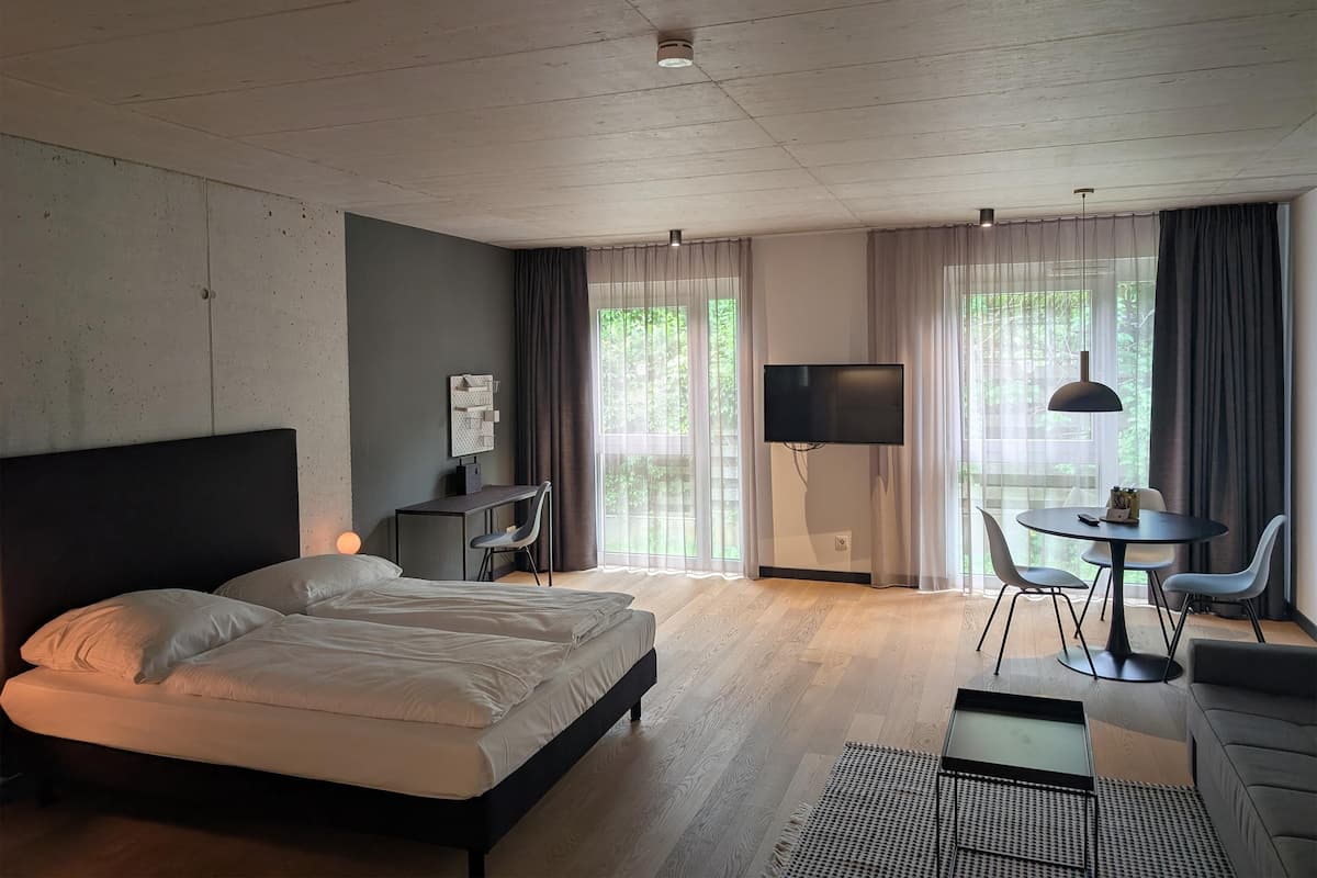 Ett modernt hotellrum med en stor säng, ett skrivbord, en TV och en matplats.