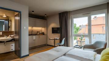 A hotel room with a bed, a desk, a TV, and a view of the outside.