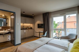 Habitación de hotel con cama, escritorio, televisión y vistas al exterior.
