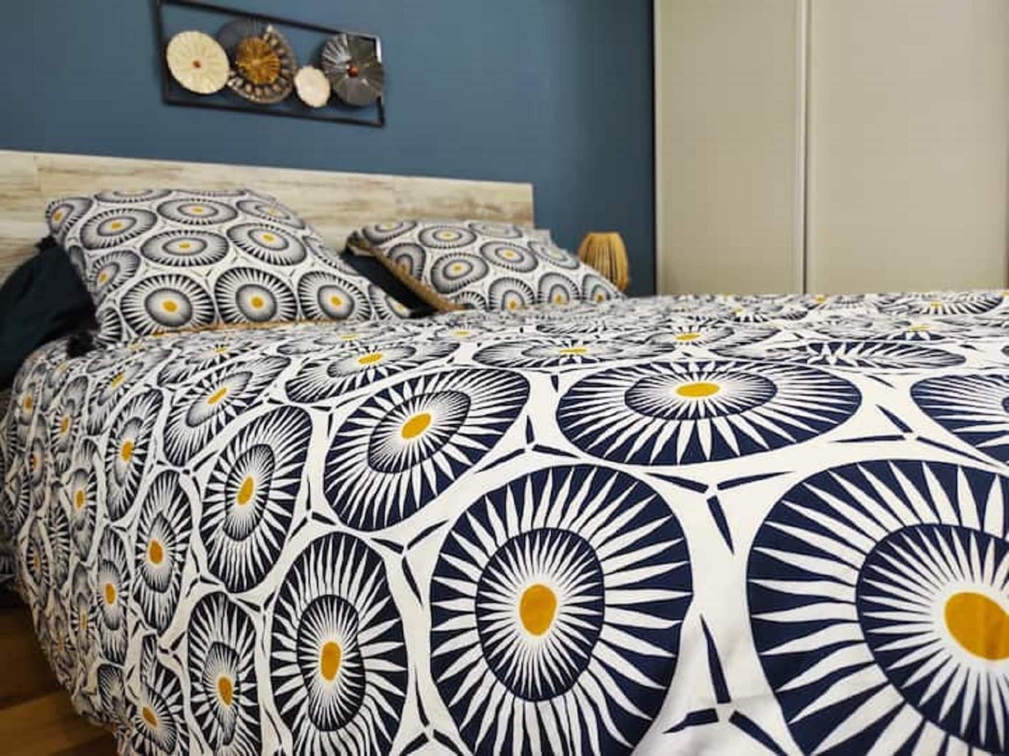 Ein Bett mit einem gemusterten Überwurf, einem Kopfteil und einer Wand mit dekorativen Tellern.