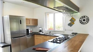 Une cuisine moderne dotée d’appareils électroménagers en acier inoxydable, d’un plan de travail en bois et d’une fenêtre laissant entrer la lumière naturelle.