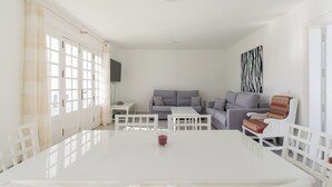 Una sala moderna con una mesa de comedor blanca, sofás grises y un sillón estampado.