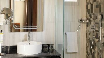 Une salle de bain moderne avec une douche à parois de verre, un lavabo blanc et un grand miroir.
