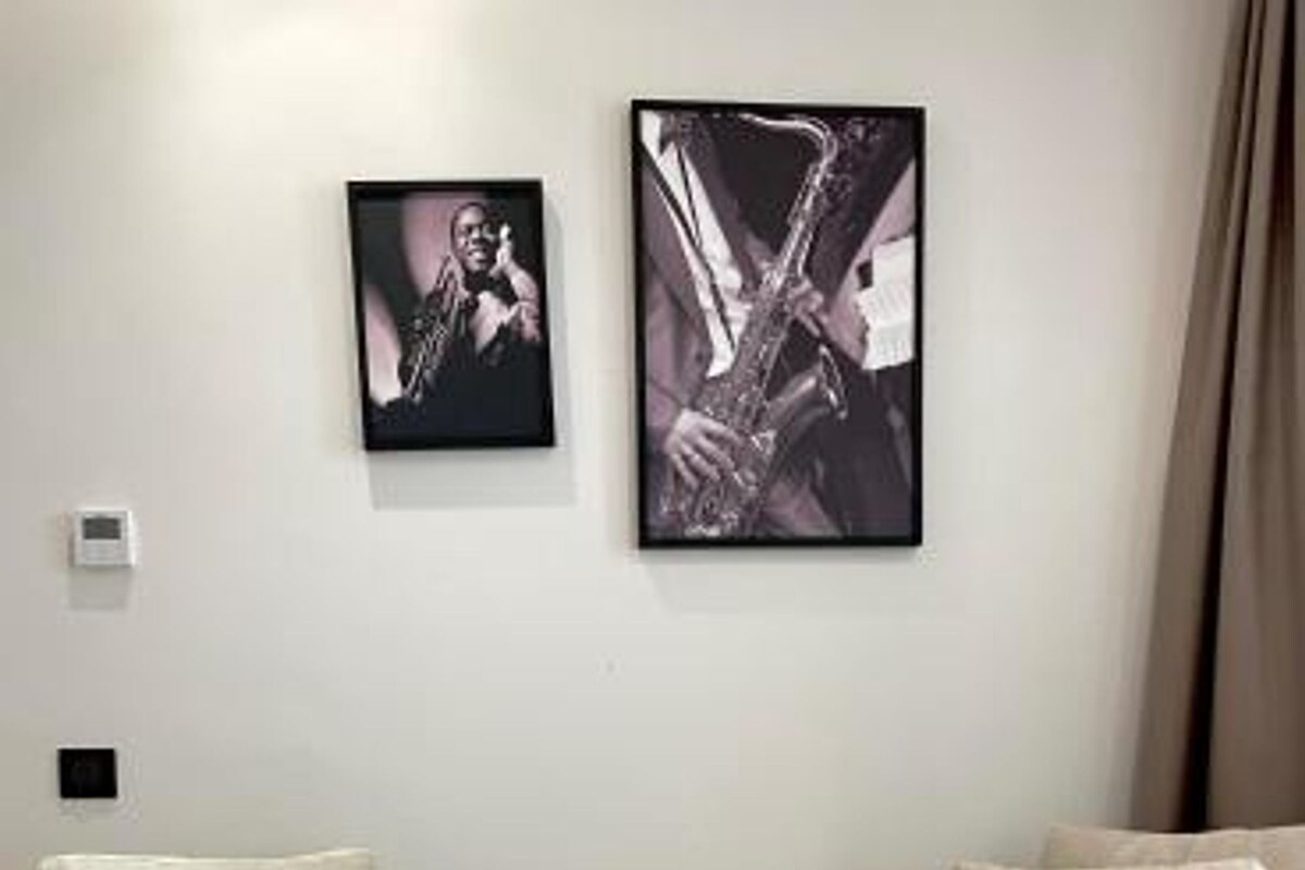 Una habitación de hotel moderna con un sofá, dos mesas de comedor con desayuno y obras de arte en la pared.